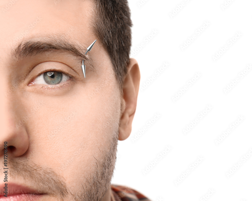 Young man with pierced eyebrow on light background, closeup
