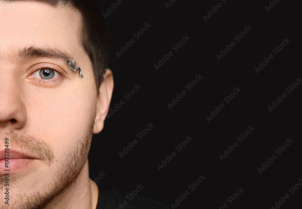 Young man with pierced eyebrow on black background Young man with pierced eyebrow on black background
