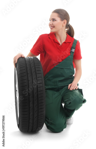 Female mechanic with car tire on white background