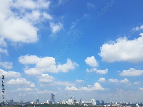 White puffy cumulus clouds computing over cityscape of Johor Bahru, Malaysia with clear blue skies © teriztdh