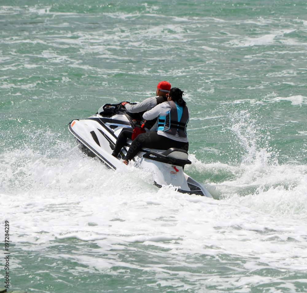 Obraz premium Young afro-american couple riding tandem on a jet. ski on the florida intra-coastal waterway off Miami Beach.
