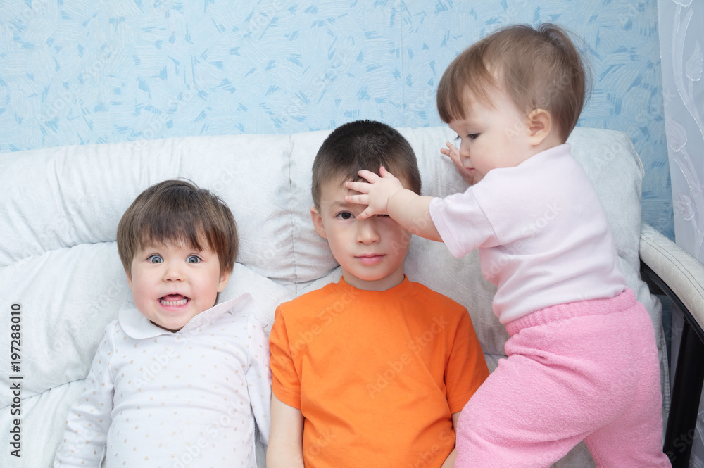 funny children mess around,playful happy laughing kids, three children different ages sitting on coach, portrait of boy, little girl and baby girl, happiness in childhood of siblings funny children mess around,playful happy laughing kids, three children different ages sitting on coach, portrait of boy, little girl and baby girl, happiness in childhood of siblings