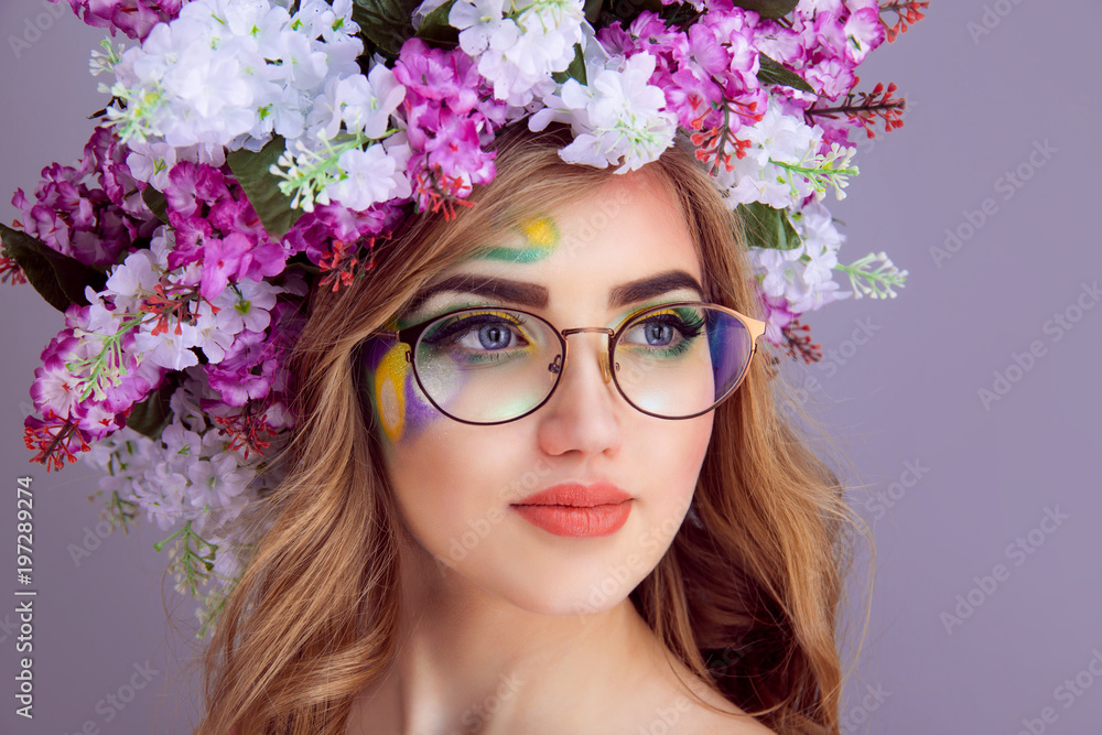 Fototapeta premium Closeup beautiful young woman with floral lilac headband in round retro eyeglasses