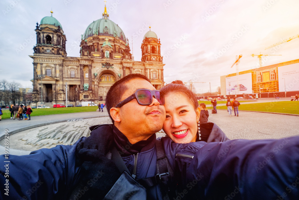 Young Couple Tourists taking selfie with mobile phone in front of Berlin Cathedral (Berliner Dom) in Berlin, Germany