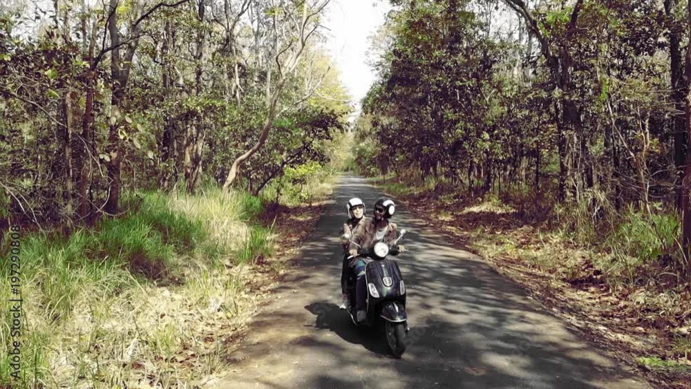 Slow motion Couple riding their scooter through forest. Slow motion Couple riding their scooter through forest.