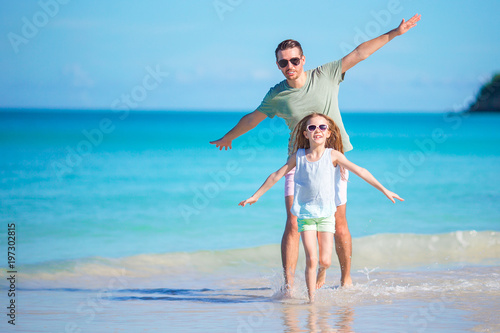 Little girl and happy dad having fun during beach vacation