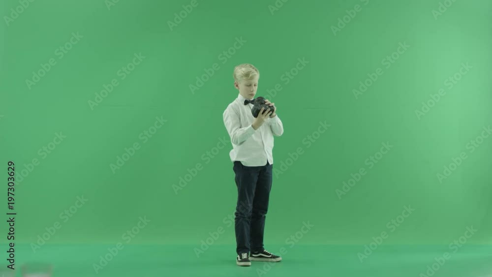 Little boy is considering a new camera turning right on a green screen Little boy is considering a new camera turning right on a green screen