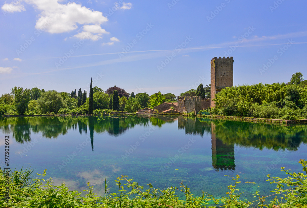 Fototapeta premium Garden of Ninfa, Italy - A natural monument with medieval ruins in stone, flowers park and an awesome torrent with little fall. Province of Latina, Lazio region, central Italy.