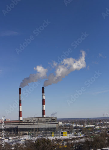 The pipe of the plant emits harmful substances into the atmosphere. Close-up on a sky background