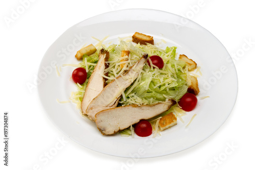Caesar salad with chicken in a plate on a white background