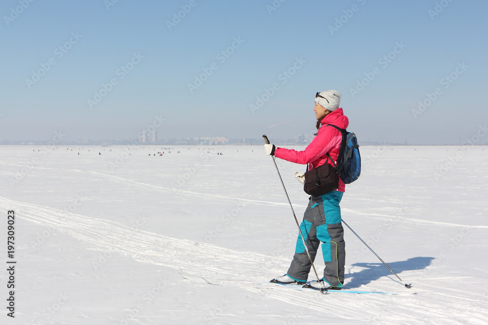 Woman in a red jacket is skiing on a snowy river in winter, Ob reservoir, Russia Woman in a red jacket is skiing on a snowy river in winter, Ob reservoir, Russia