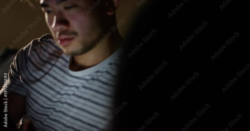 4K Young man relaxing at home late at night, browsing the internet on digital tablet 4K Young man relaxing at home late at night, browsing the internet on digital tablet