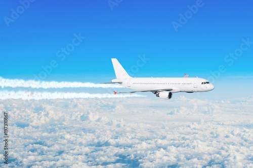 Passenger plane flying at flight level with the contrails of the engines above the clouds blue sky.