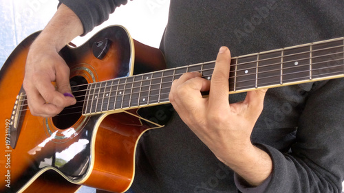 Guitarist performance barre on acoustic guitar correctly clamp chord etalon game mediator close-up photo