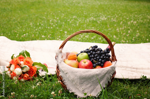 Wicker basket with fruit and wine in the meadow in summer