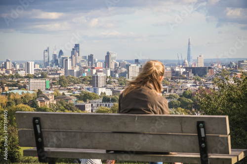 Back view of a tourist looking over London city skyline from Parliament Hill in Hampstead Heath photo