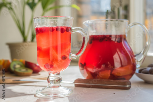 A traditional Scandinavian drink with cranberries and berries in a glass and jug