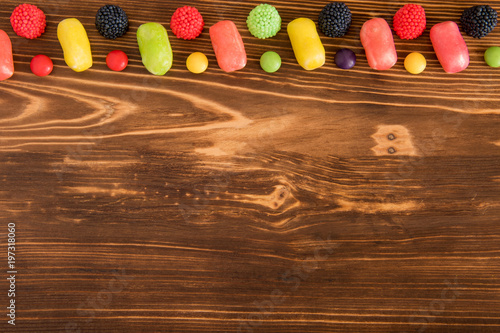 Colored candy on dark wooden background with copespace photo