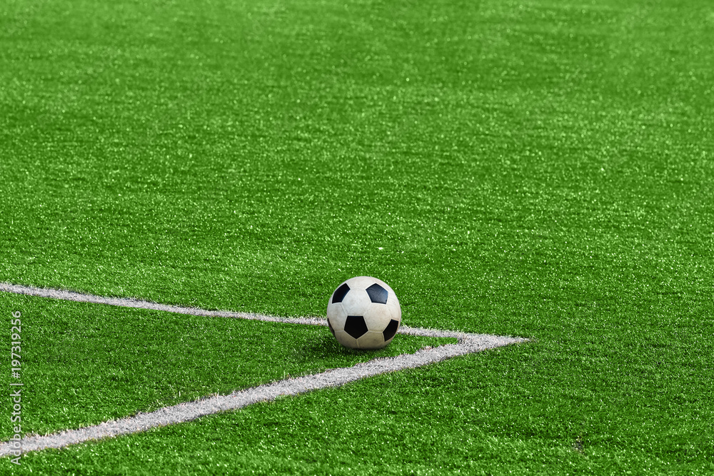 Fototapeta A soccer ball framed by white corner markings on a green football field.