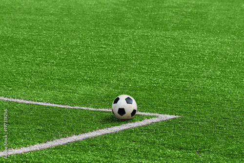 A soccer ball framed by white corner markings on a green football field. © SKfoto