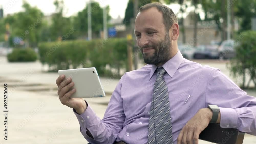 Happy businessman watching movie on tablet sitting on bench in city
Happy businessman watching movie on tablet sitting on bench in city