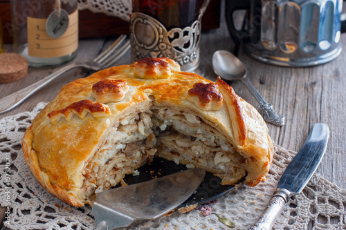 Festive national Russian pie from chicken, pancakes, rice, mushrooms. Cornice cut, selective focus photo