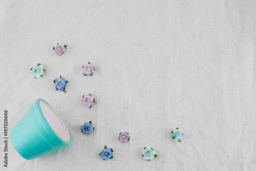 Pastel blue pot and blue tone rose paper flowers on muslin fabric with copy space Pastel blue pot and blue tone rose paper flowers on muslin fabric with copy space