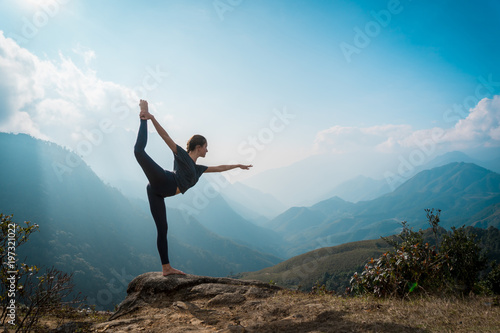 Woman training yoga, mountains on background photo