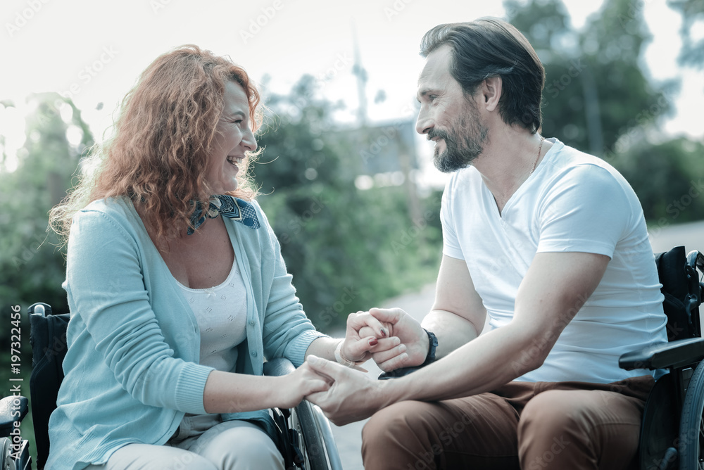 My support. Cheerful invalid female sitting on her wheelchair near her man and expressing positivity while looking forward My support. Cheerful invalid female sitting on her wheelchair near her man and expressing positivity while looking forward