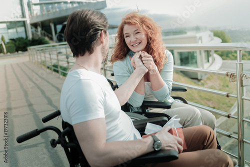 In all ears. Positive delighted red haired female person holding hands together while looking forward, feeling happiness