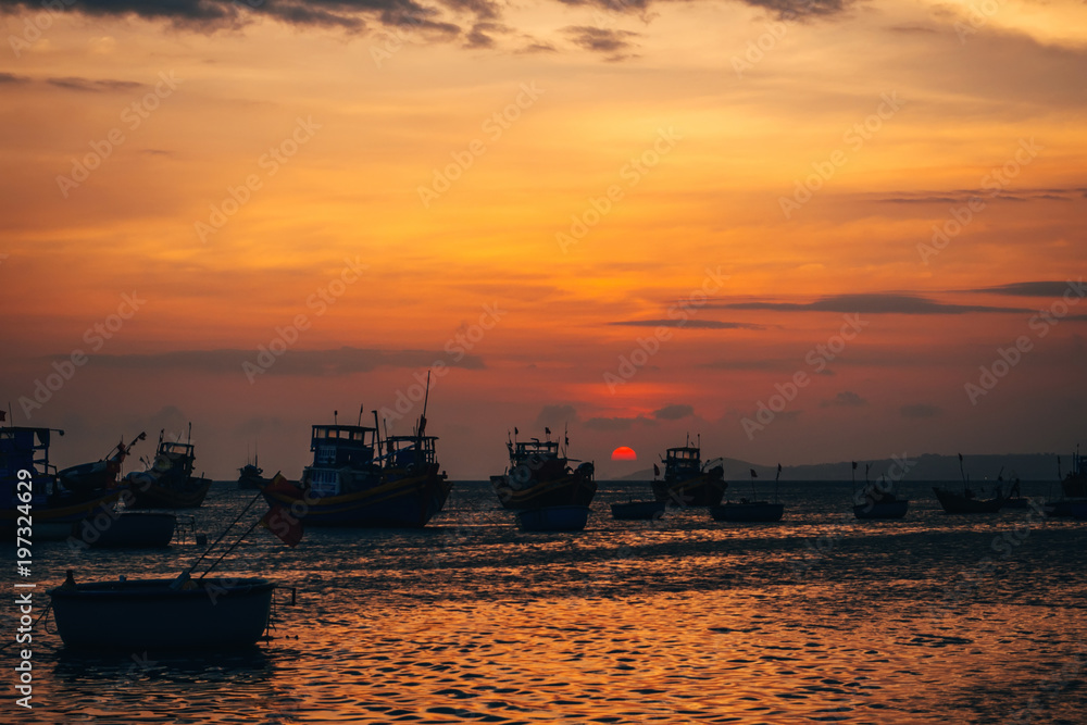 traditional Vietnamese fishing boats on the sea in the background of orange sunset