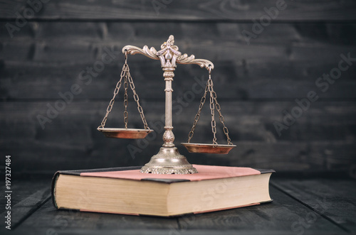  Scales of Justice and law books on a wooden background.