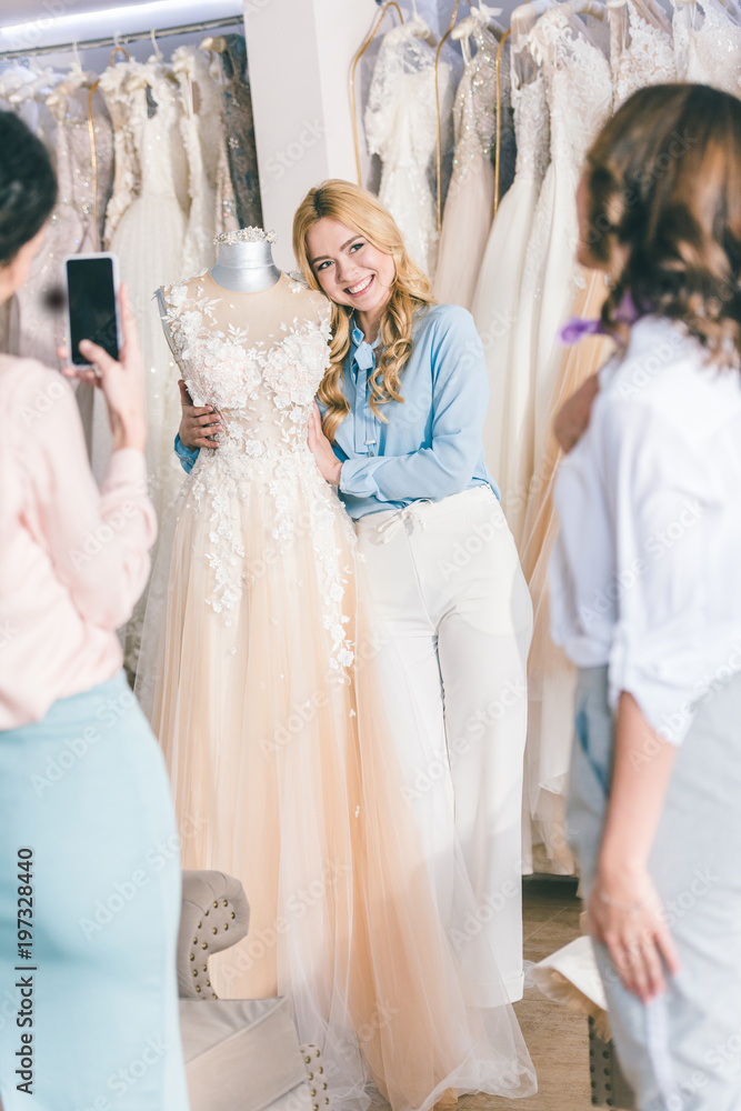 Bridesmaids and bride taking photo while choosing dress in wedding fashion shop Bridesmaids and bride taking photo while choosing dress in wedding fashion shop