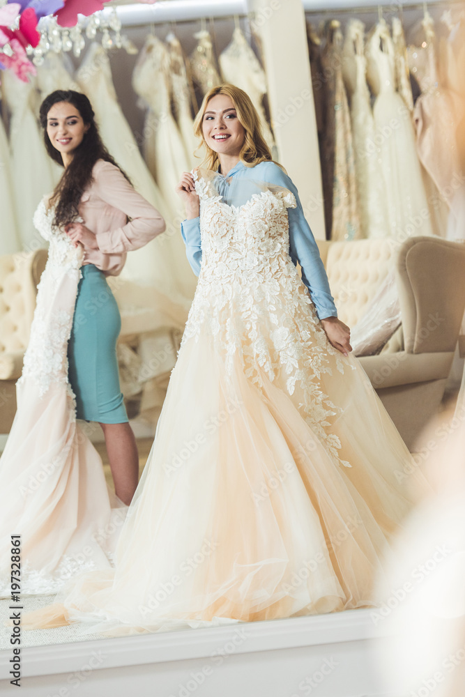  Brides holding lace dresses in wedding salon