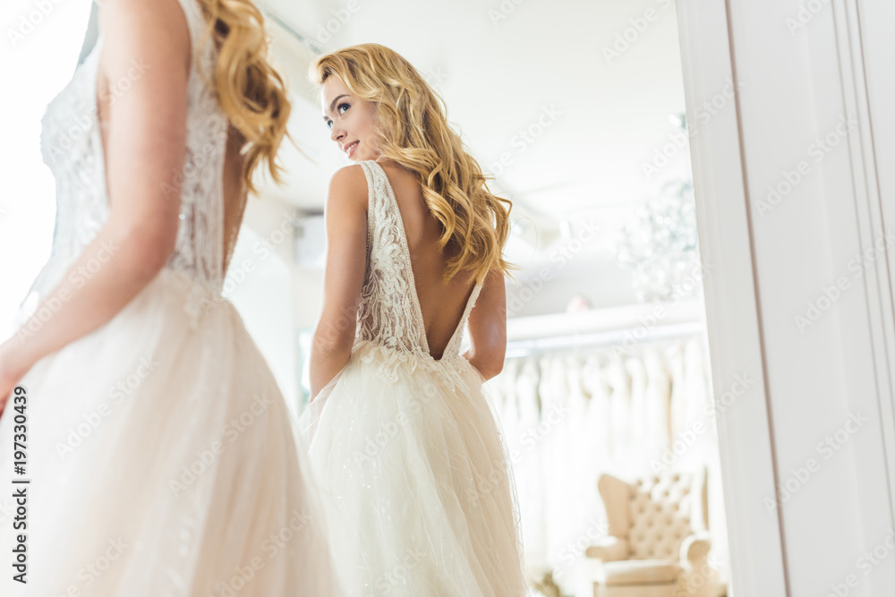 Stylish bride in lace dress by mirror in wedding salon Stylish bride in lace dress by mirror in wedding salon