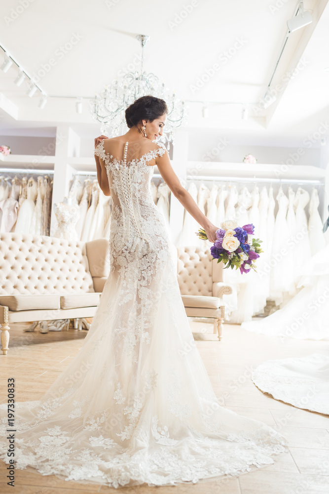Beautiful bride with floral bouquet in wedding fashion shop