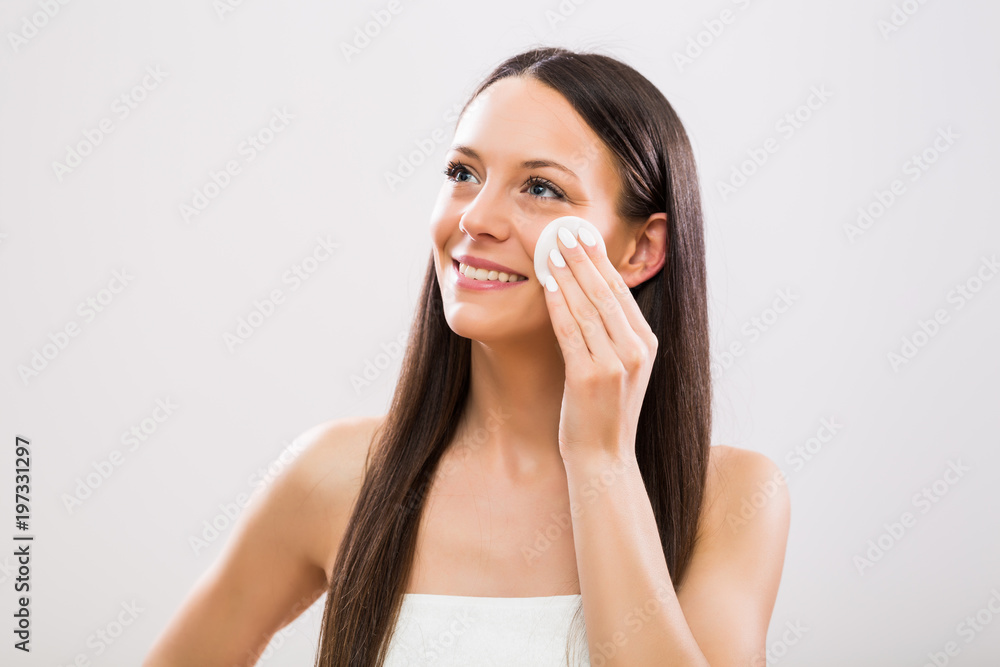 Beautiful brunette woman cleaning her face with cotton pad. Beautiful brunette woman cleaning her face with cotton pad.