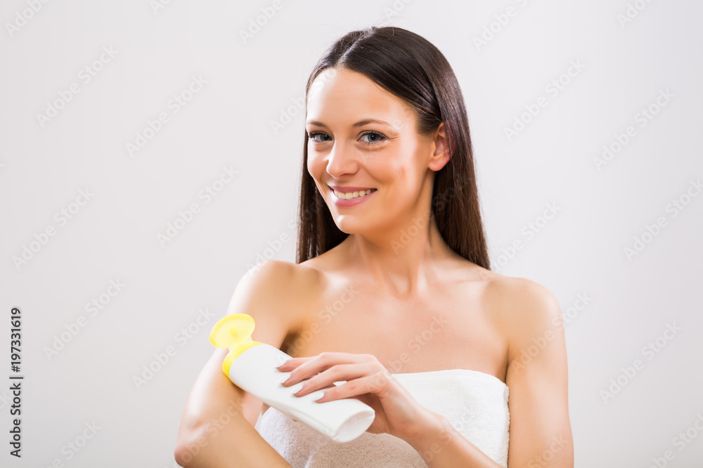 Beautiful woman applying moisturizer on her arm on gray background. Beautiful woman applying moisturizer on her arm on gray background.