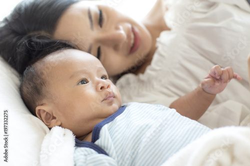 Portrait of Mother and new born baby on a white bed.