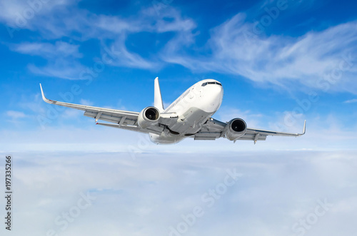 White aircraft flies climbs height, flight level high in the sky above the clouds blue sky.