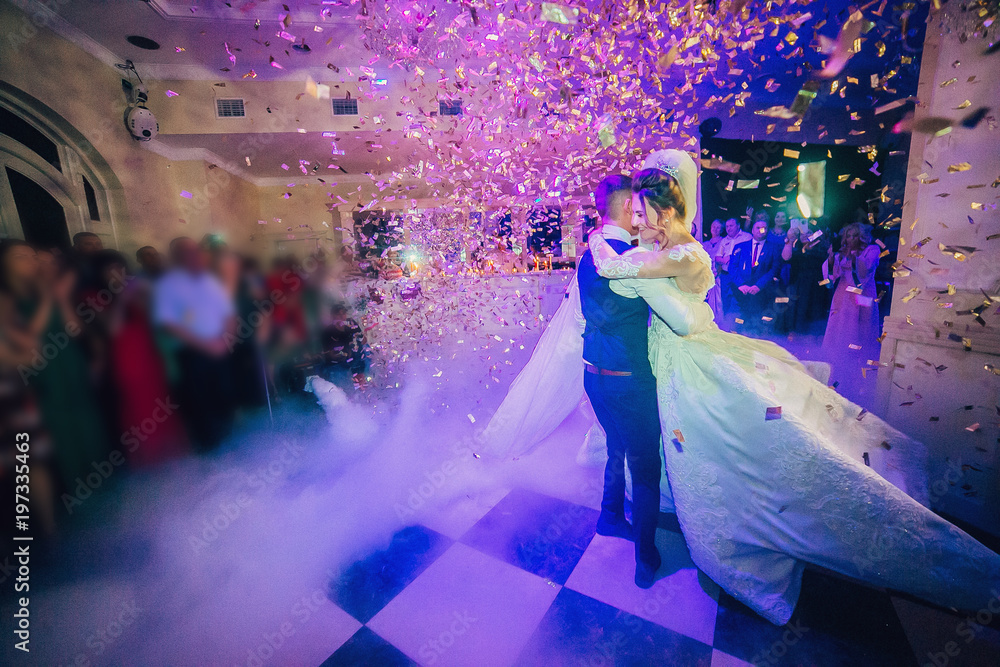 Amazing first wedding dance of newlywed with different colorful light and heavy smoke on restaurant.
