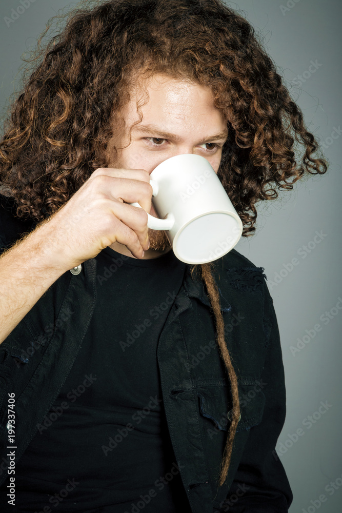 Young athletic ginger man holding a coffee mug, studio portrait
