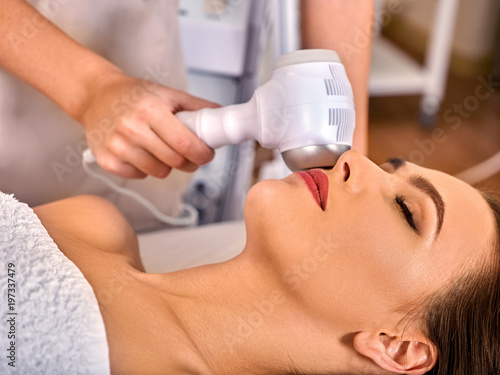 Ultrasonic facial treatment ultrasound face machine. Woman receiving electric lift massage spa salon. Electronic stimulation female muscles. Improvement of skin condition.