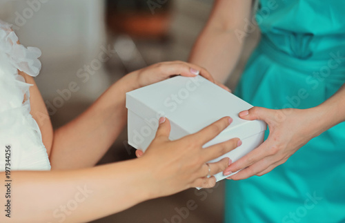 Female hands holding gift close-up. Bride and her bridesmaid smiling happy