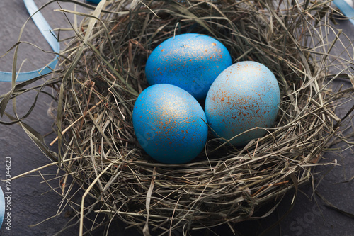 Easter background. Colored eggs in nest on gray stone surface