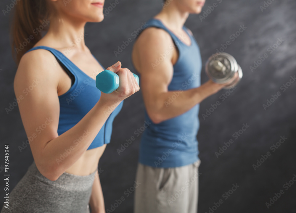 Fitness couple making exercise with dumbbells Fitness couple making exercise with dumbbells