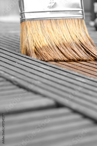 Staining wooden decking in a garden with a paintbrush with selective color