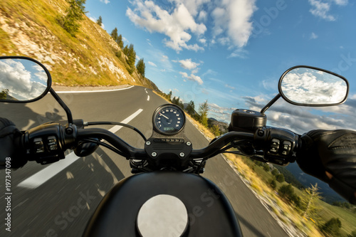 POV of motorbiker holding steering bar, riding in Alps