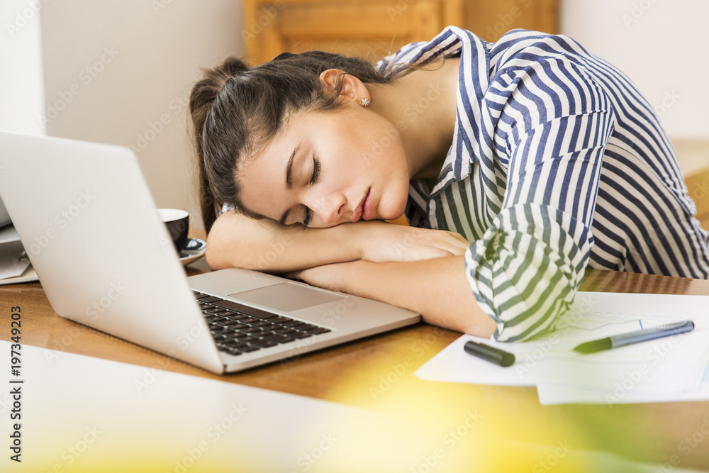 Young woman sleeping in front of laptop at home desk Young woman sleeping in front of laptop at home desk