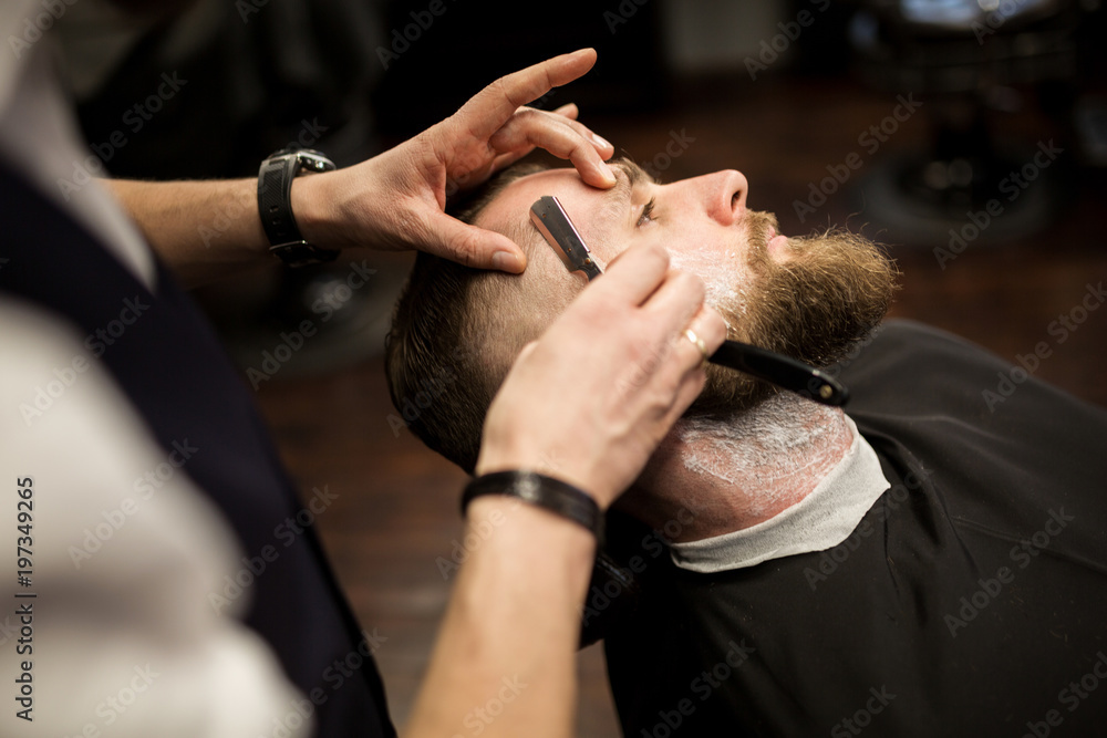 Young man being shaved by professional barber